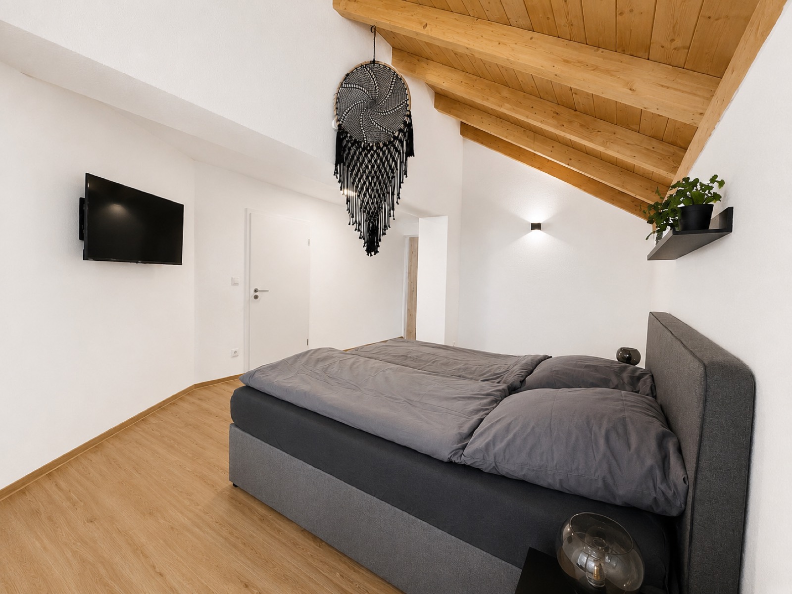 Schlafzimmer mit Doppelbett unter der Dachschräge in der Ferienwohnung am Soier See