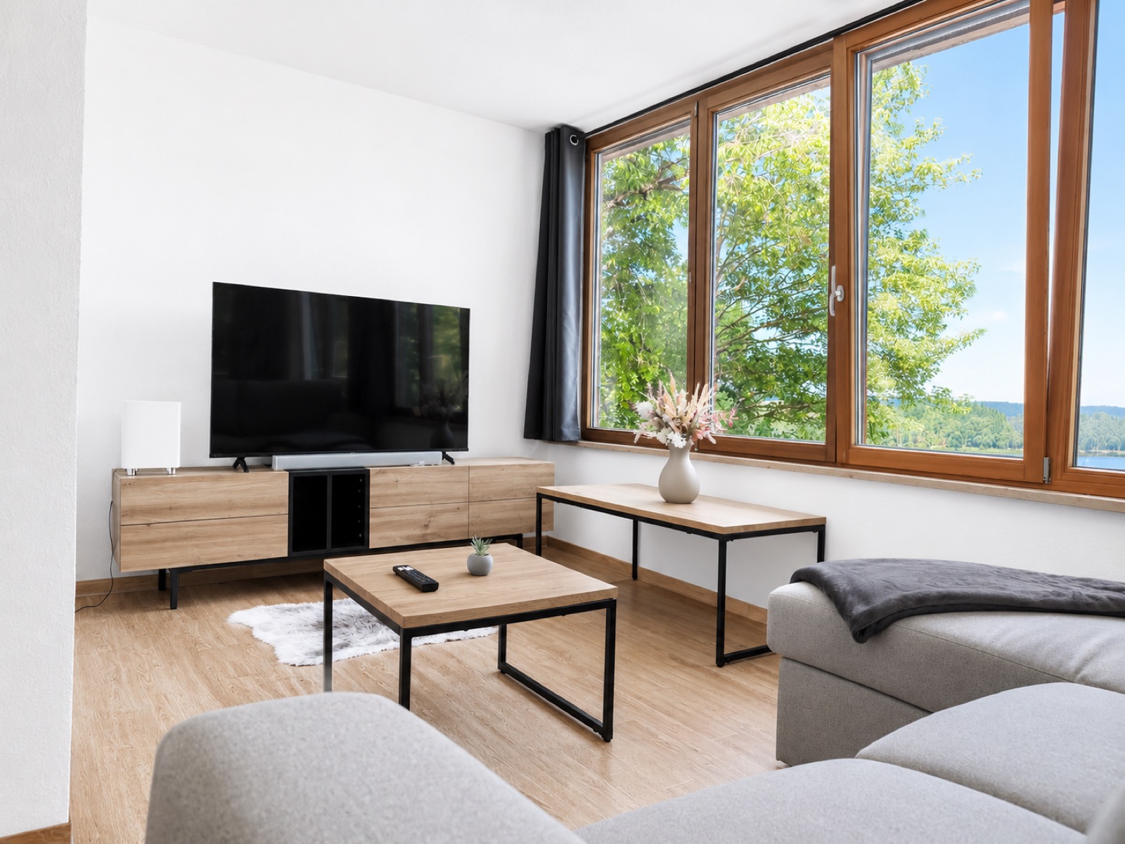 Wohnzimmer der Ferienwohnung am Soier See mit Sofa, Smart-TV und Ausblick ins Grüne
